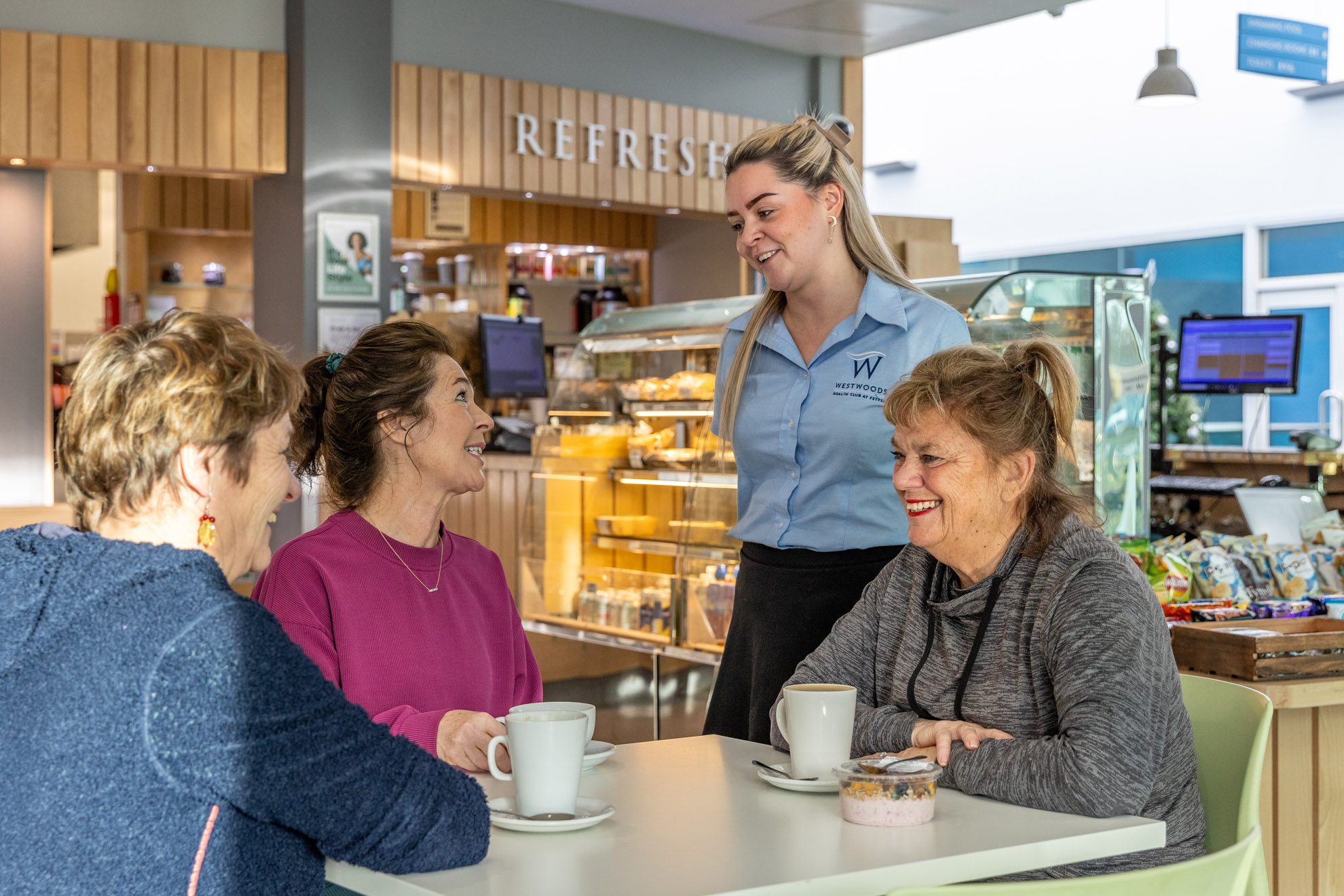 female members sitting together and laughing whilst enjoying lunch in café refresh within Westwoods Health Club