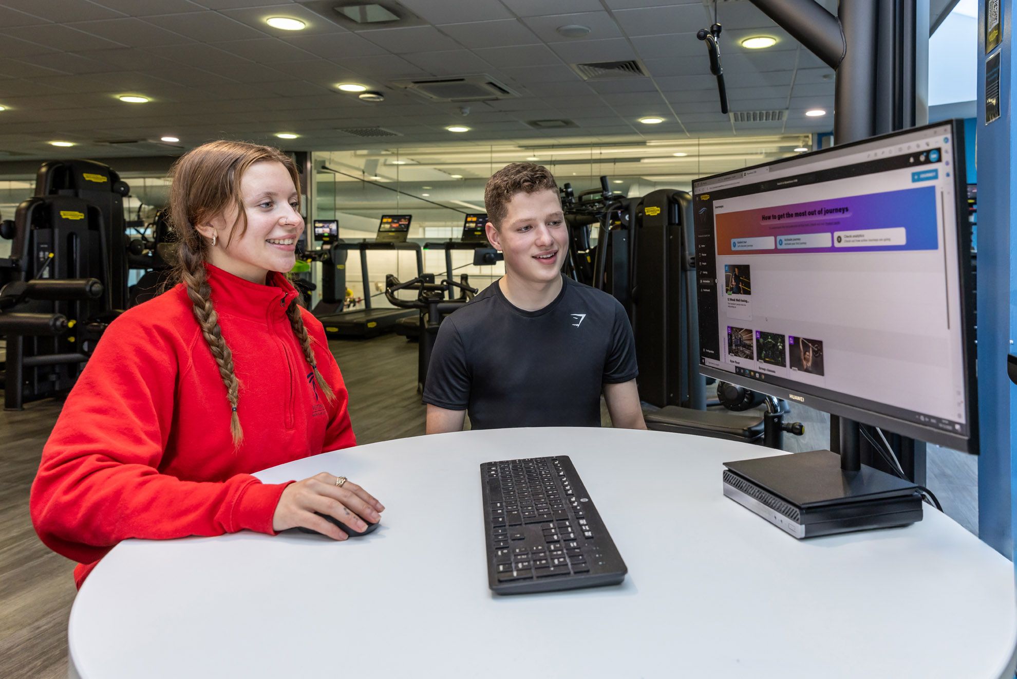Fitness instructor with a member at the MyWellness Station in the gym at Westwoods Health Club whilst looking at their Fitnees programme