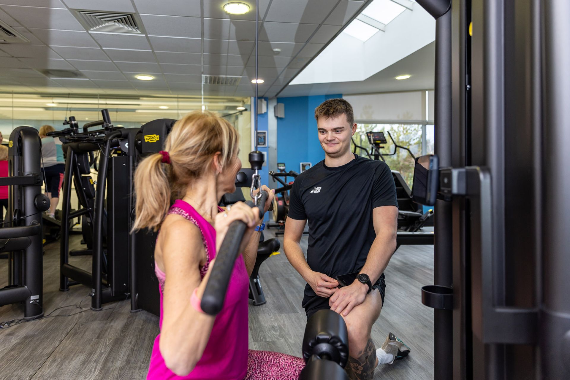 Jack mellor personal trainer at Westwoods Health Club working with a client to on their fitness routine on the lat pulldown weights machine