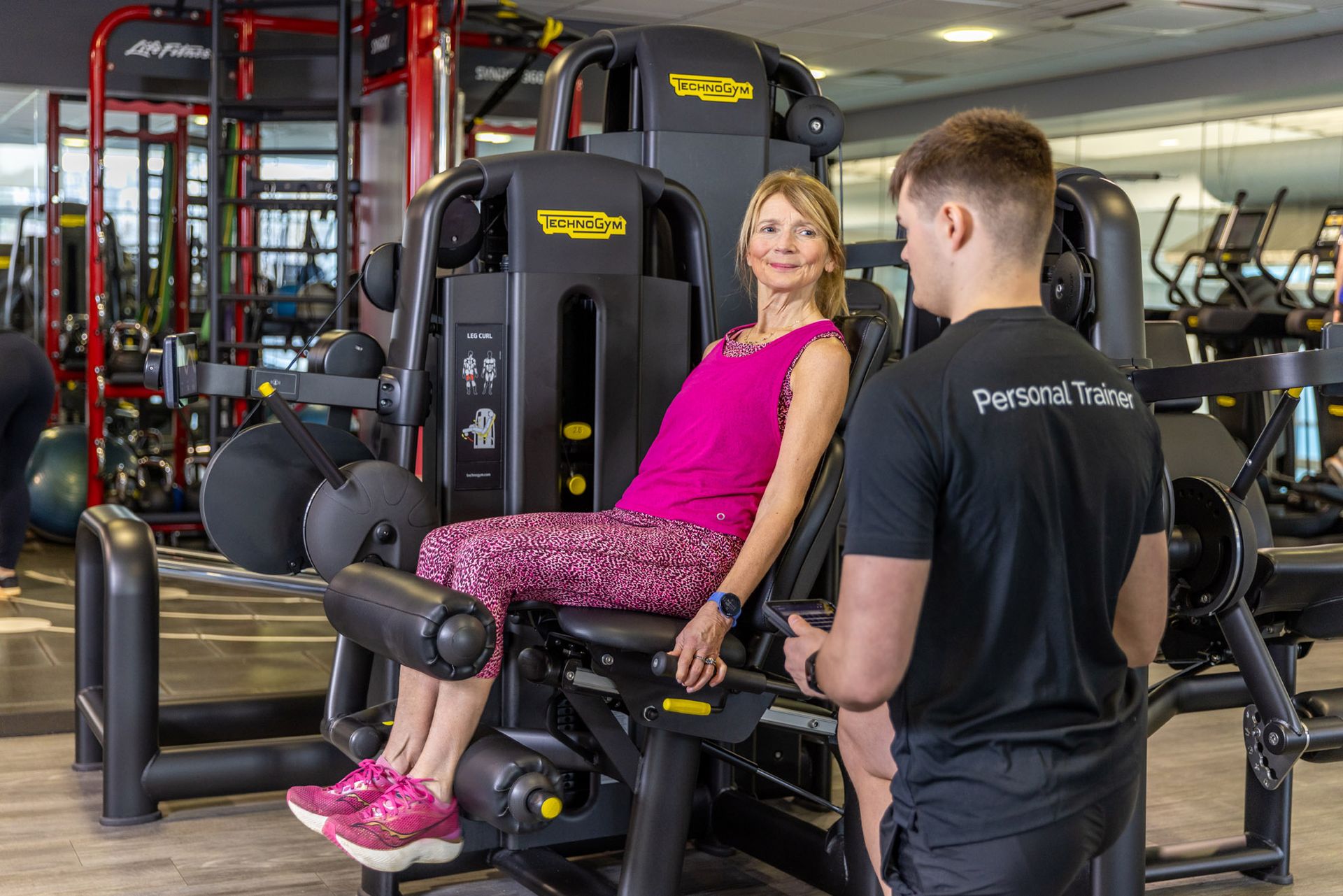 Jack mellor personal trainer at Westwoods Health Club working with a client to on their fitness routine using the leg extension weights machine