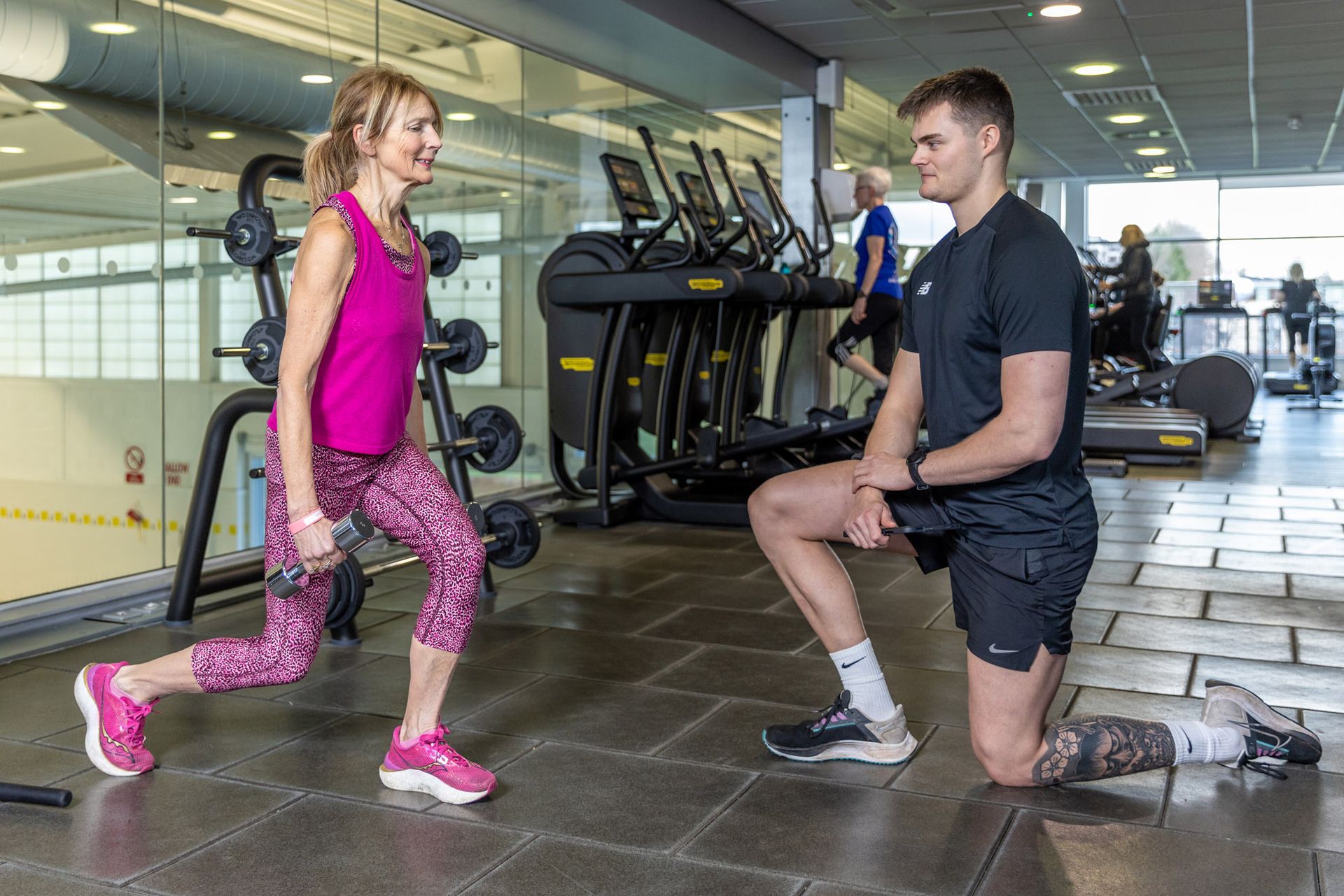 Jack mellor personal trainer at Westwoods Health Club working with a client to on their fitness routine doing linges in the free weights area